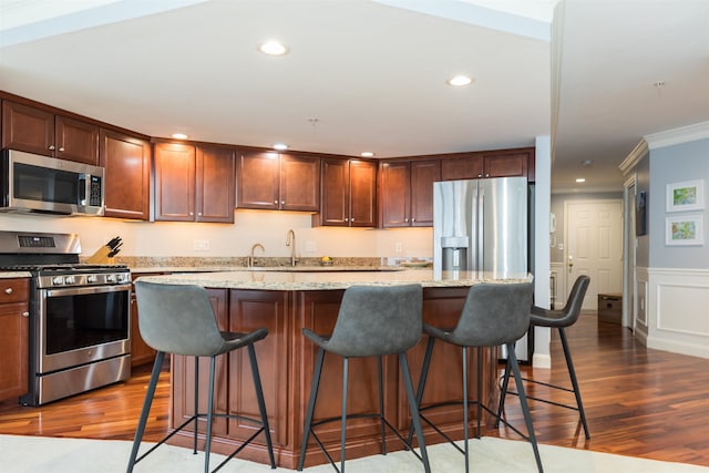 kitchen with appliances with stainless steel finishes, crown molding, dark wood-style floors, a center island, and recessed lighting
