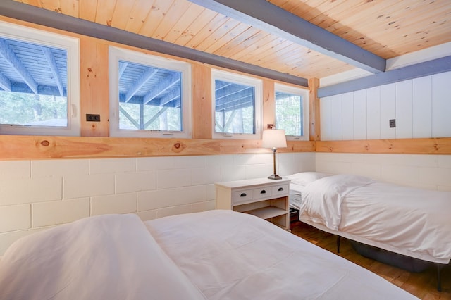 bedroom featuring wooden ceiling, multiple windows, wood finished floors, and beamed ceiling
