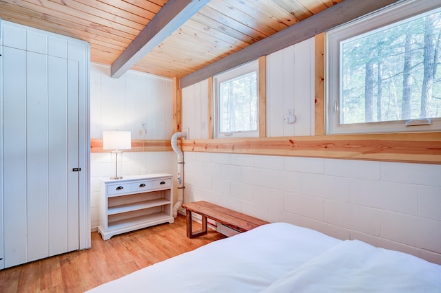 bedroom with wooden ceiling, light wood-style floors, concrete block wall, and beamed ceiling