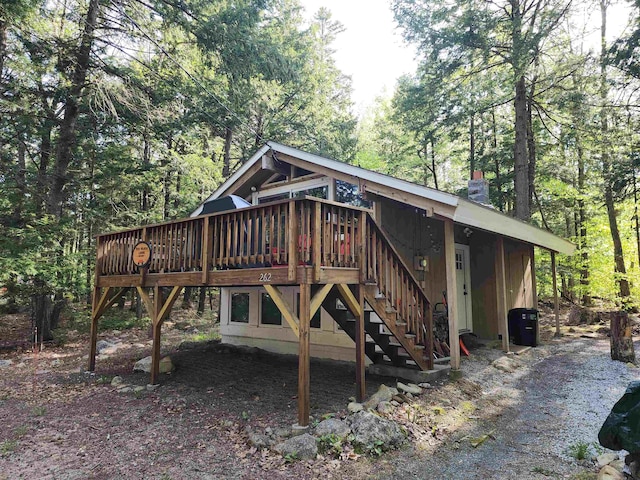 back of house featuring stairway, a wooden deck, a chimney, and a forest view