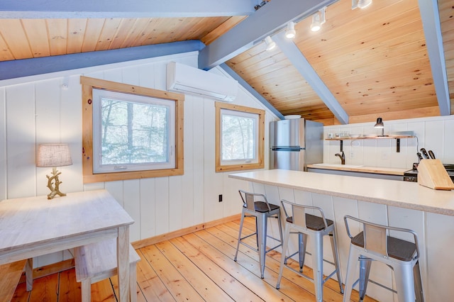 kitchen with a wall mounted air conditioner, freestanding refrigerator, light wood-type flooring, baseboards, and rail lighting