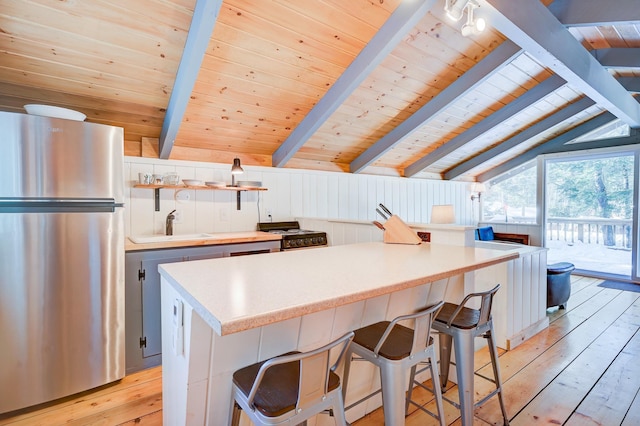 kitchen featuring freestanding refrigerator, wooden ceiling, light wood-style flooring, a sink, and light countertops