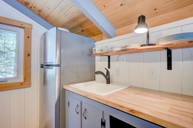 kitchen with open shelves, a sink, butcher block countertops, freestanding refrigerator, and wooden ceiling