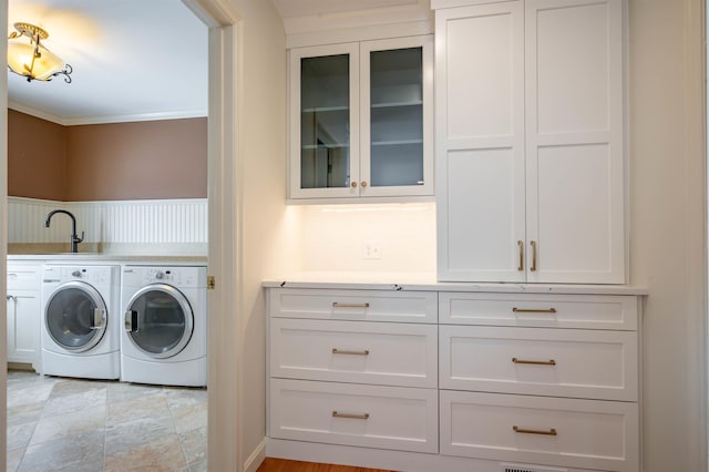 washroom with cabinet space, washer and clothes dryer, and crown molding
