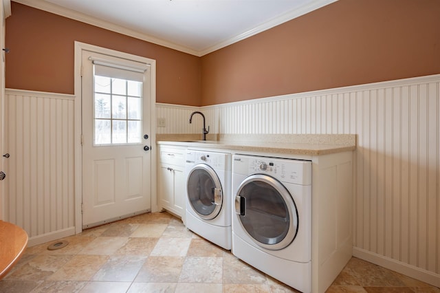 laundry room with washing machine and clothes dryer, wainscoting, crown molding, baseboards, and cabinet space