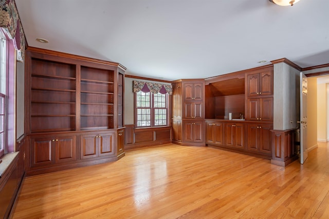 unfurnished living room with light wood finished floors, crown molding, and a sink
