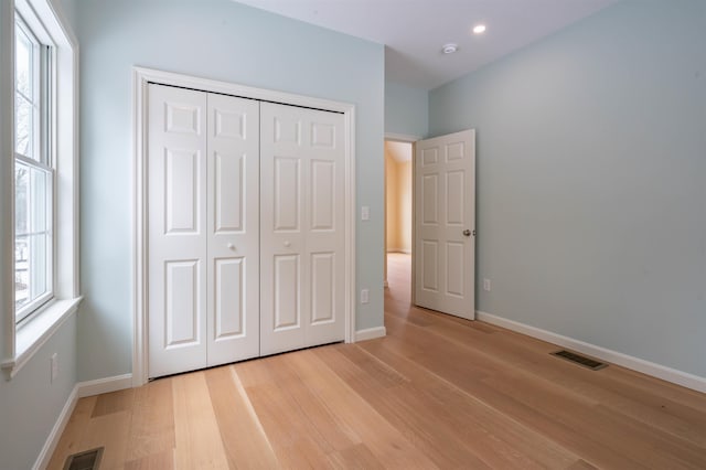 unfurnished bedroom with light wood-style flooring, baseboards, a closet, and recessed lighting