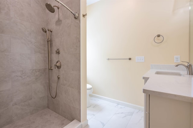 full bath featuring marble finish floors, vanity, a tile shower, toilet, and baseboards