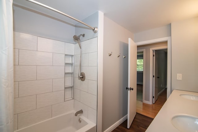 full bath with shower / tub combo, wood finished floors, baseboards, and a sink
