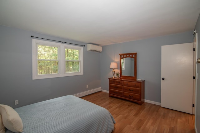 bedroom featuring a baseboard radiator, a wall mounted AC, wood finished floors, and baseboards