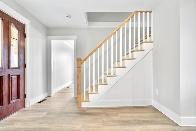 entryway with baseboards, wood finished floors, and stairway
