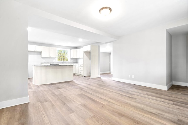 unfurnished living room with baseboards and light wood-type flooring
