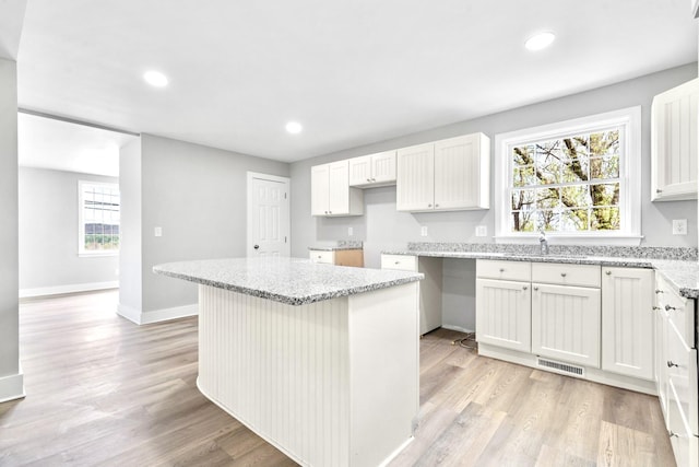 kitchen with light stone countertops, light wood-style flooring, baseboards, and recessed lighting
