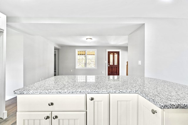 kitchen featuring light stone countertops, white cabinetry, and wood finished floors