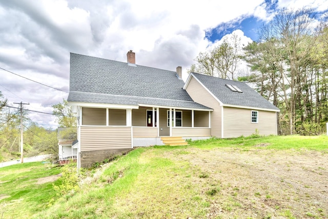 back of house with covered porch, a chimney, and roof with shingles