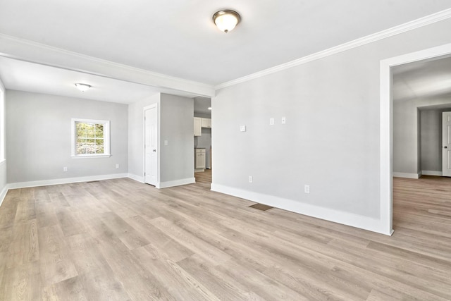 spare room with crown molding, baseboards, and light wood-style floors