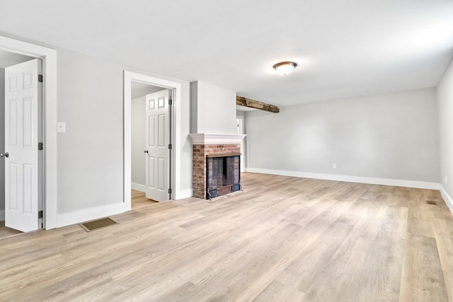 unfurnished living room featuring light wood finished floors, baseboards, and a brick fireplace