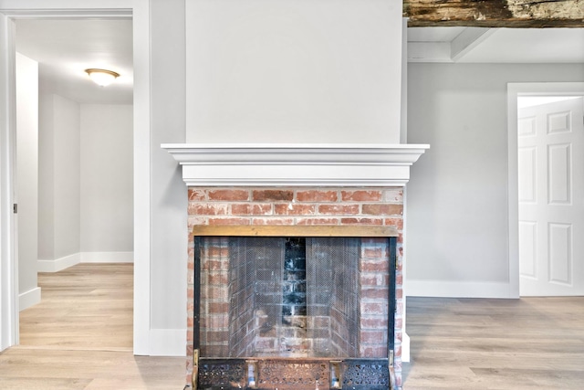 detailed view of a brick fireplace, wood finished floors, and baseboards