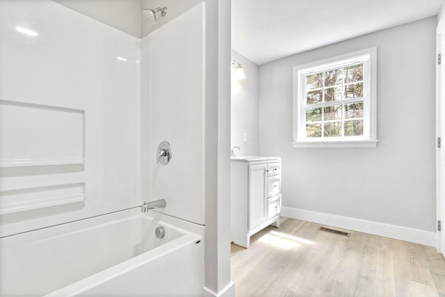 full bathroom with baseboards, washtub / shower combination, wood finished floors, and vanity