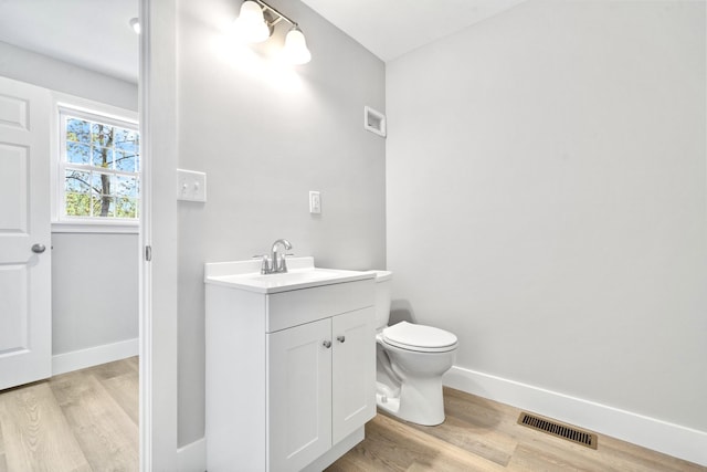 bathroom with wood finished floors, baseboards, vanity, and toilet