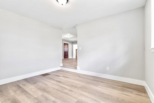 spare room with baseboards and light wood finished floors