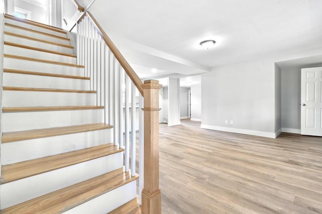 staircase featuring baseboards and wood finished floors
