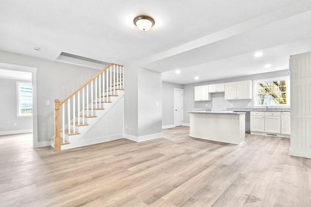 kitchen with baseboards, a kitchen island, light wood-style flooring, white cabinetry, and recessed lighting