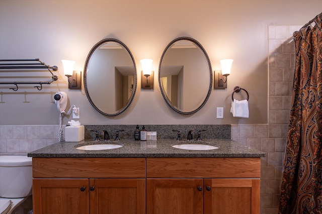 bathroom with tile walls, toilet, and double vanity