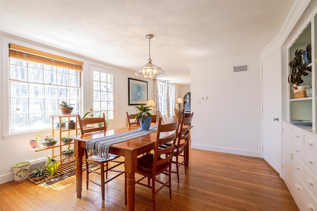 dining area featuring a chandelier, light wood-style flooring, and baseboards