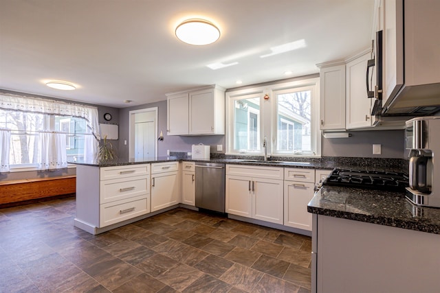 kitchen featuring dishwasher, a sink, a peninsula, and white cabinetry