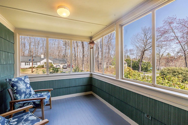 unfurnished sunroom with wood-type flooring, crown molding, and baseboards