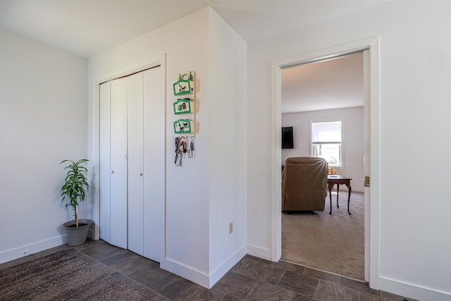 hallway featuring baseboards and stone finish flooring