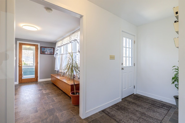foyer featuring plenty of natural light, baseboards, and stone finish flooring