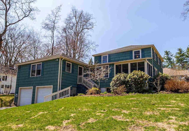 view of front of house with stairs, an attached garage, and a front yard
