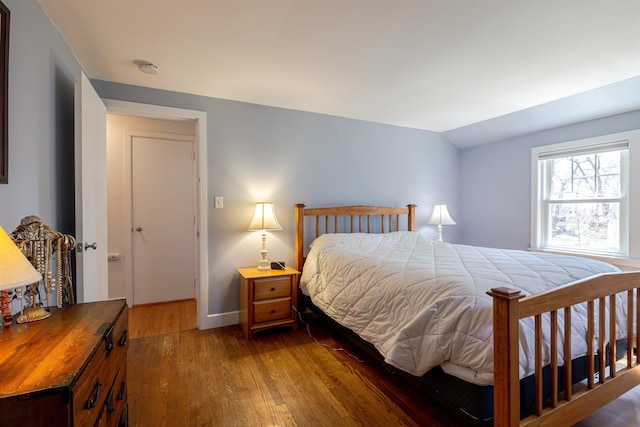 bedroom with wood finished floors, baseboards, and vaulted ceiling