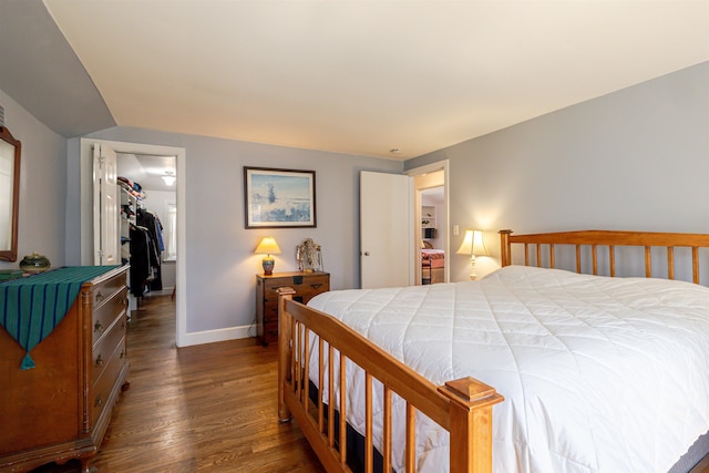 bedroom featuring dark wood-type flooring, a closet, a spacious closet, baseboards, and lofted ceiling