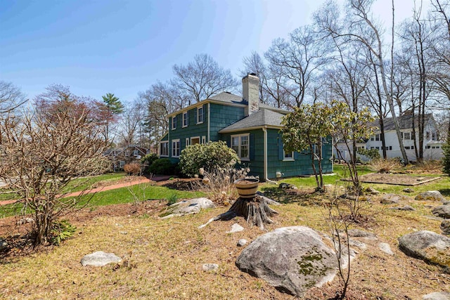 view of side of property with a chimney and roof with shingles