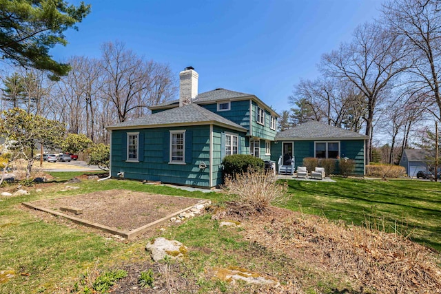 rear view of property featuring a chimney, roof with shingles, and a yard