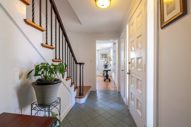 foyer entrance featuring dark tile patterned flooring, stairway, and ornamental molding