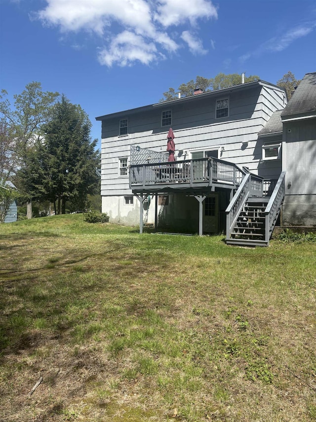 rear view of property with a wooden deck, a lawn, and stairs