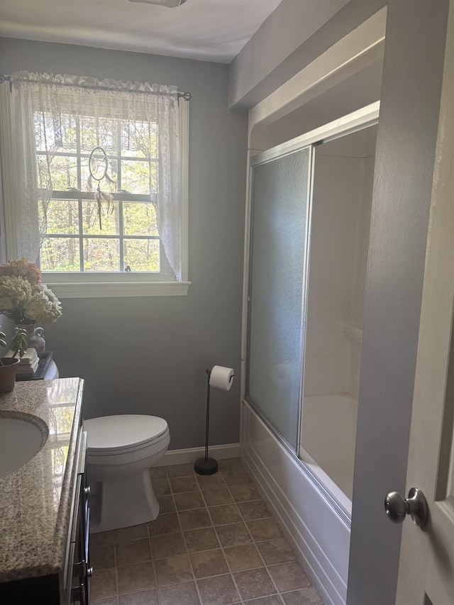 bathroom featuring vanity, toilet, combined bath / shower with glass door, baseboards, and tile patterned floors