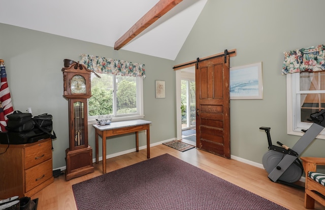 foyer entrance featuring beamed ceiling, light wood finished floors, a barn door, baseboards, and high vaulted ceiling