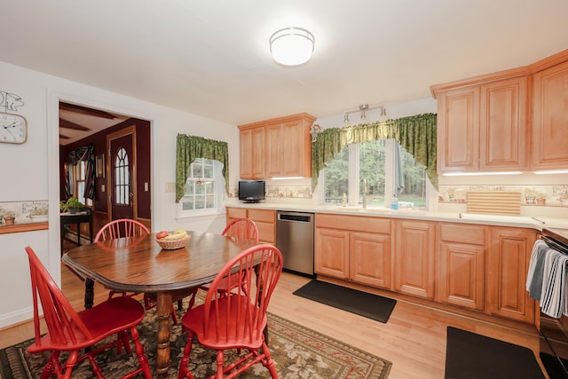 kitchen featuring stainless steel dishwasher, light wood-style floors, a sink, light brown cabinetry, and decorative backsplash