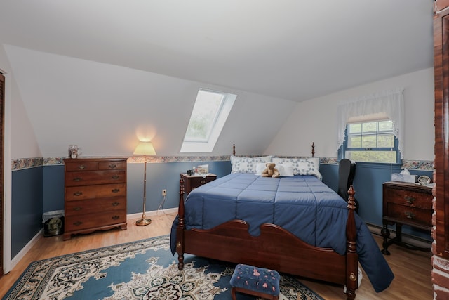 bedroom with a skylight, wood finished floors, and lofted ceiling