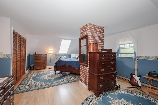 bedroom featuring wood finished floors, a closet, a skylight, and a baseboard radiator