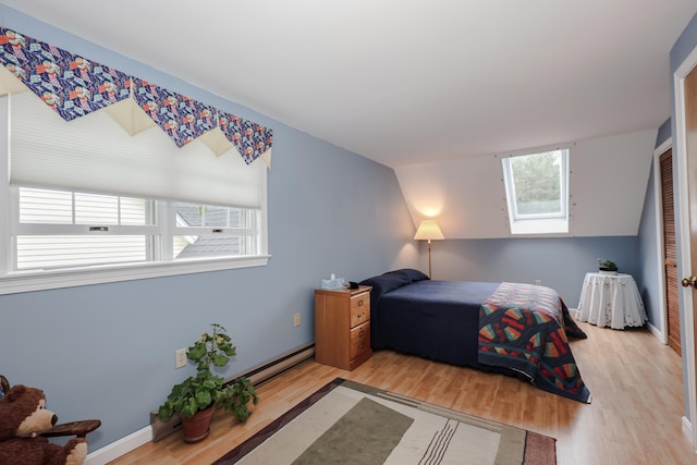 bedroom featuring multiple windows, baseboard heating, and wood finished floors