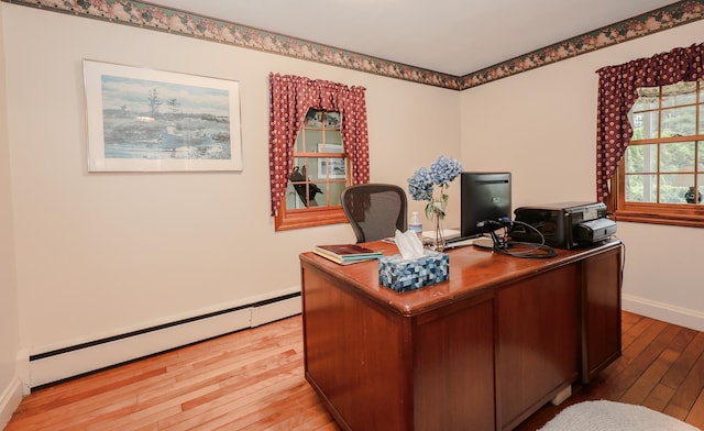 office area with a baseboard heating unit, light wood-style flooring, and baseboards