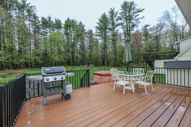wooden terrace with area for grilling, a yard, outdoor dining space, and a hot tub