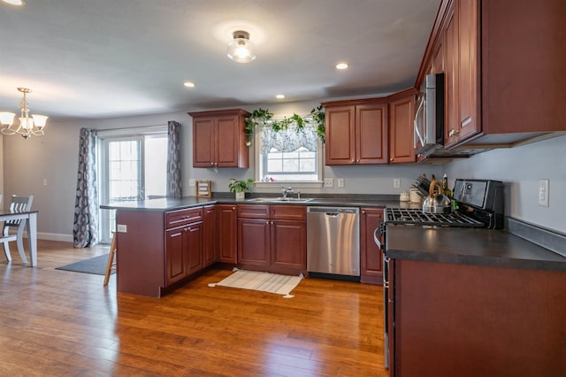 kitchen with stainless steel appliances, a peninsula, dark countertops, plenty of natural light, and recessed lighting