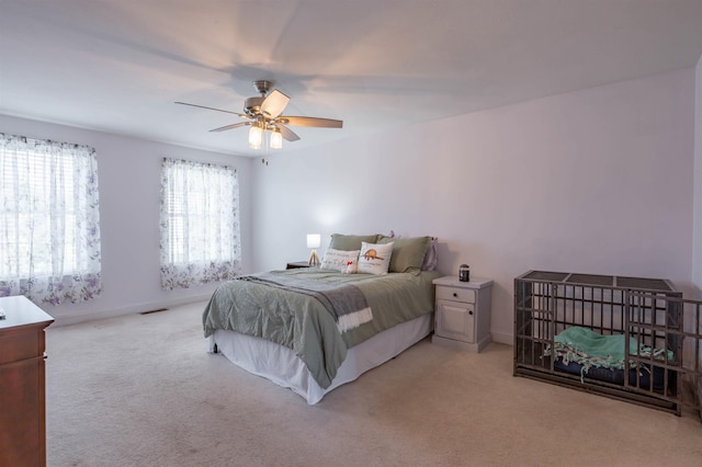bedroom featuring light colored carpet, ceiling fan, and baseboards